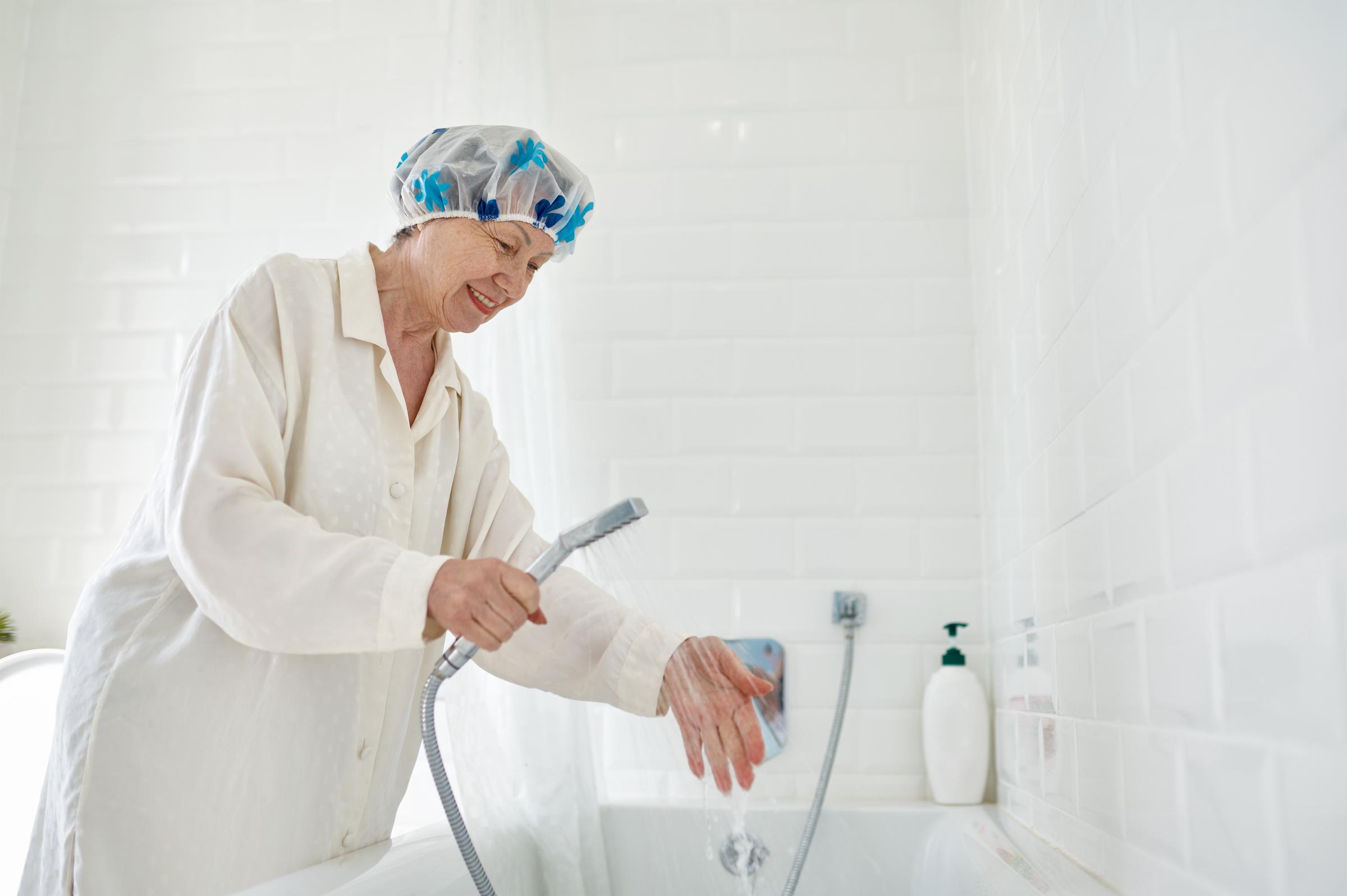 Kobieta sprawdzająca temperaturę wody przed wzięciem prysznica | Źródło: Shutterstock