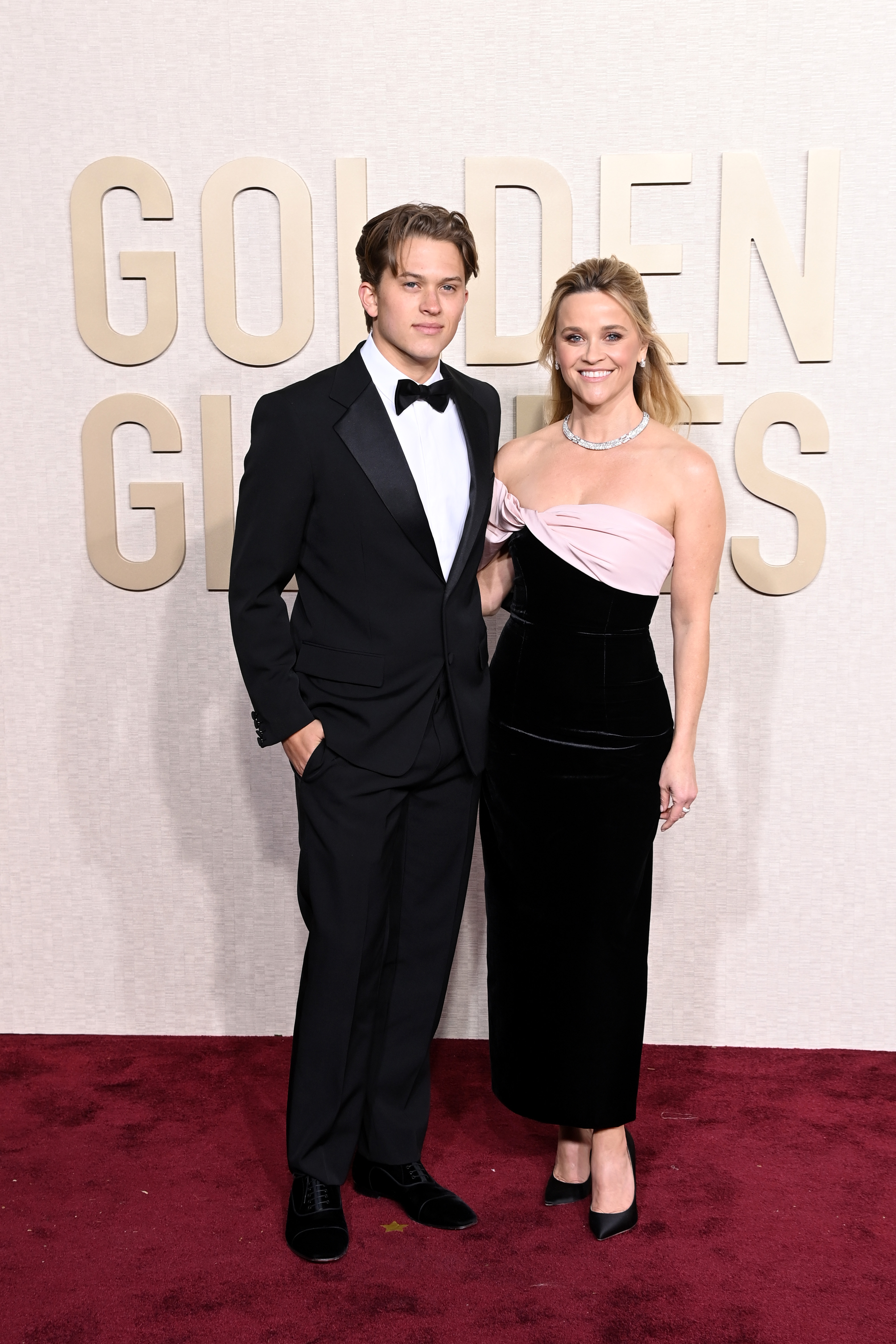 Diakon Phillippe i Reese Witherspoon pozują na czerwonym dywanie podczas 81. corocznej gali rozdania Złotych Globów – on w smokingu, a ona w czarno-różowej sukni. | Źródło: Getty Images