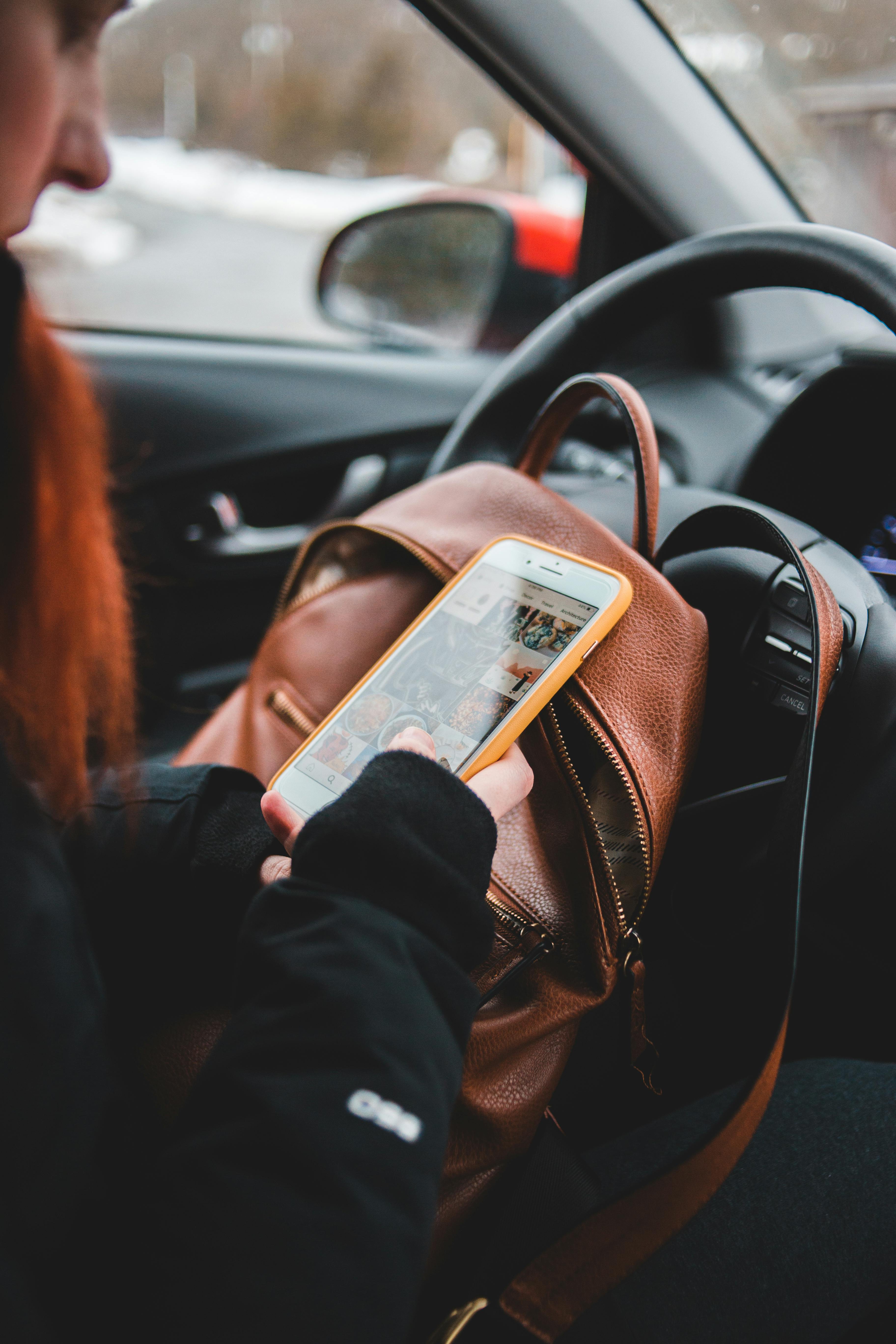Kobieta sprawdzająca swój telefon z wnętrza samochodu | Źródło: Pexels