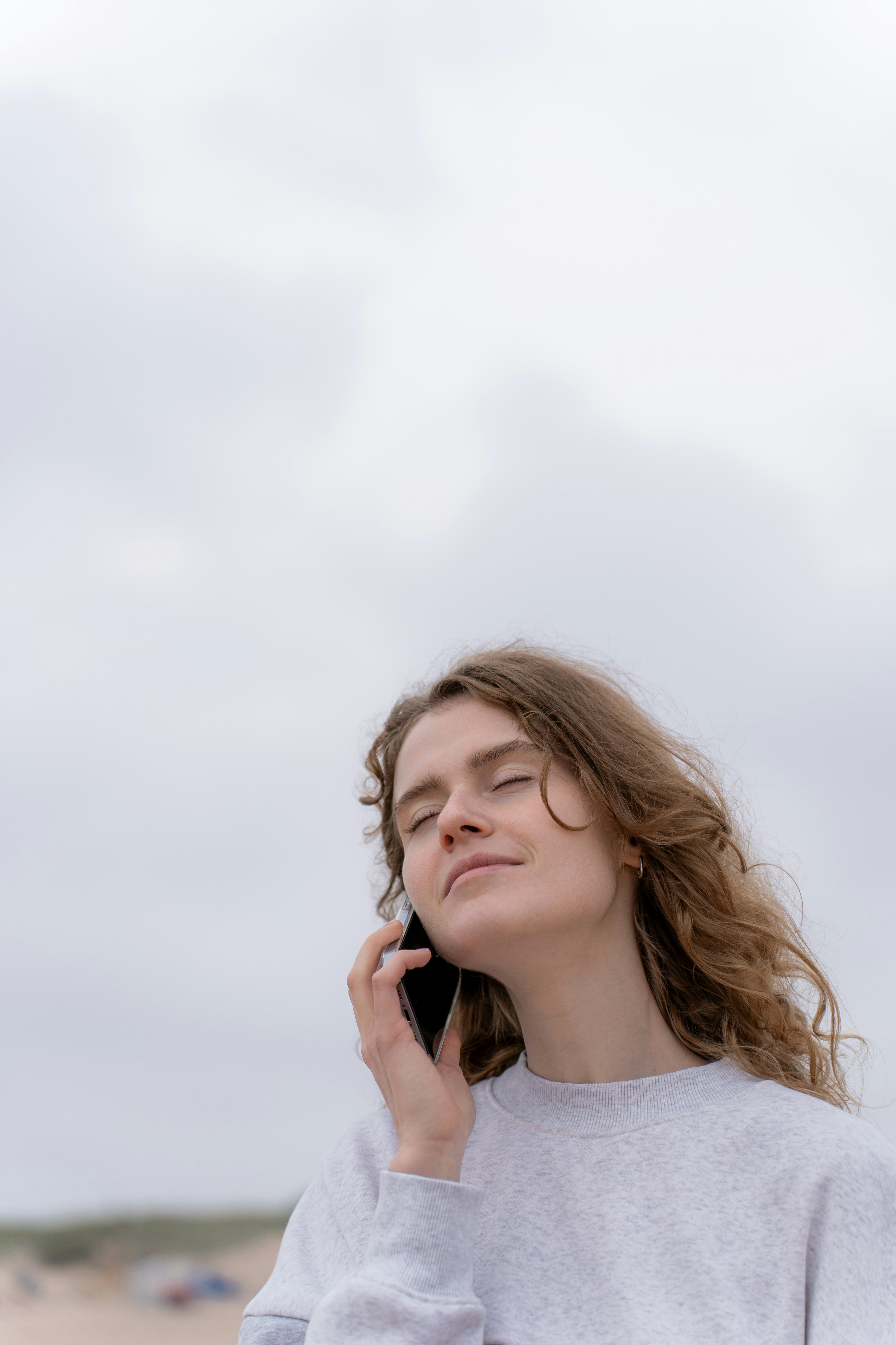 Kobieta z zamkniętymi oczami rozmawiająca przez telefon | Źródło: Unsplash
