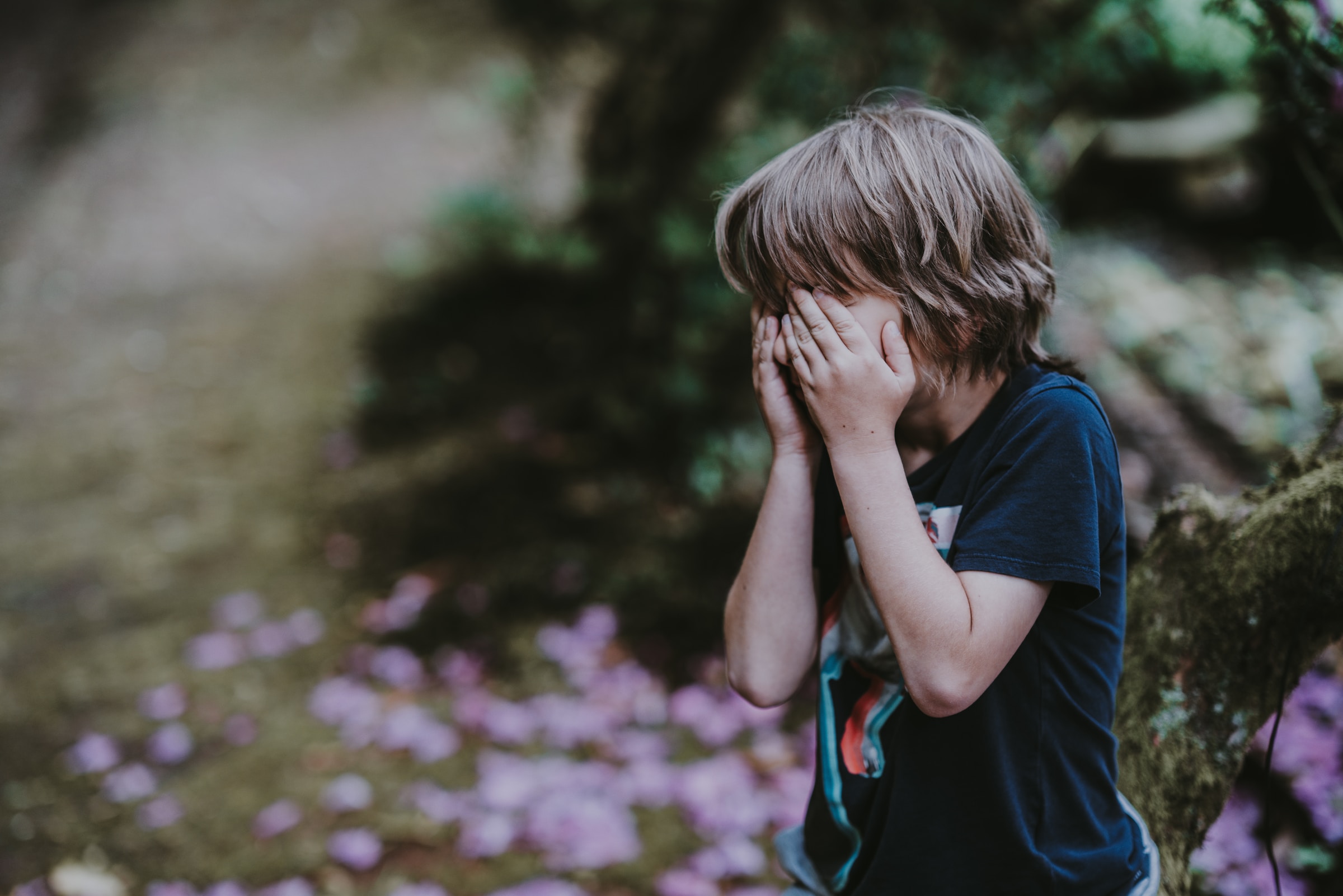 Mały chłopiec zakrywający oczy i płaczący | Źródło: Unsplash