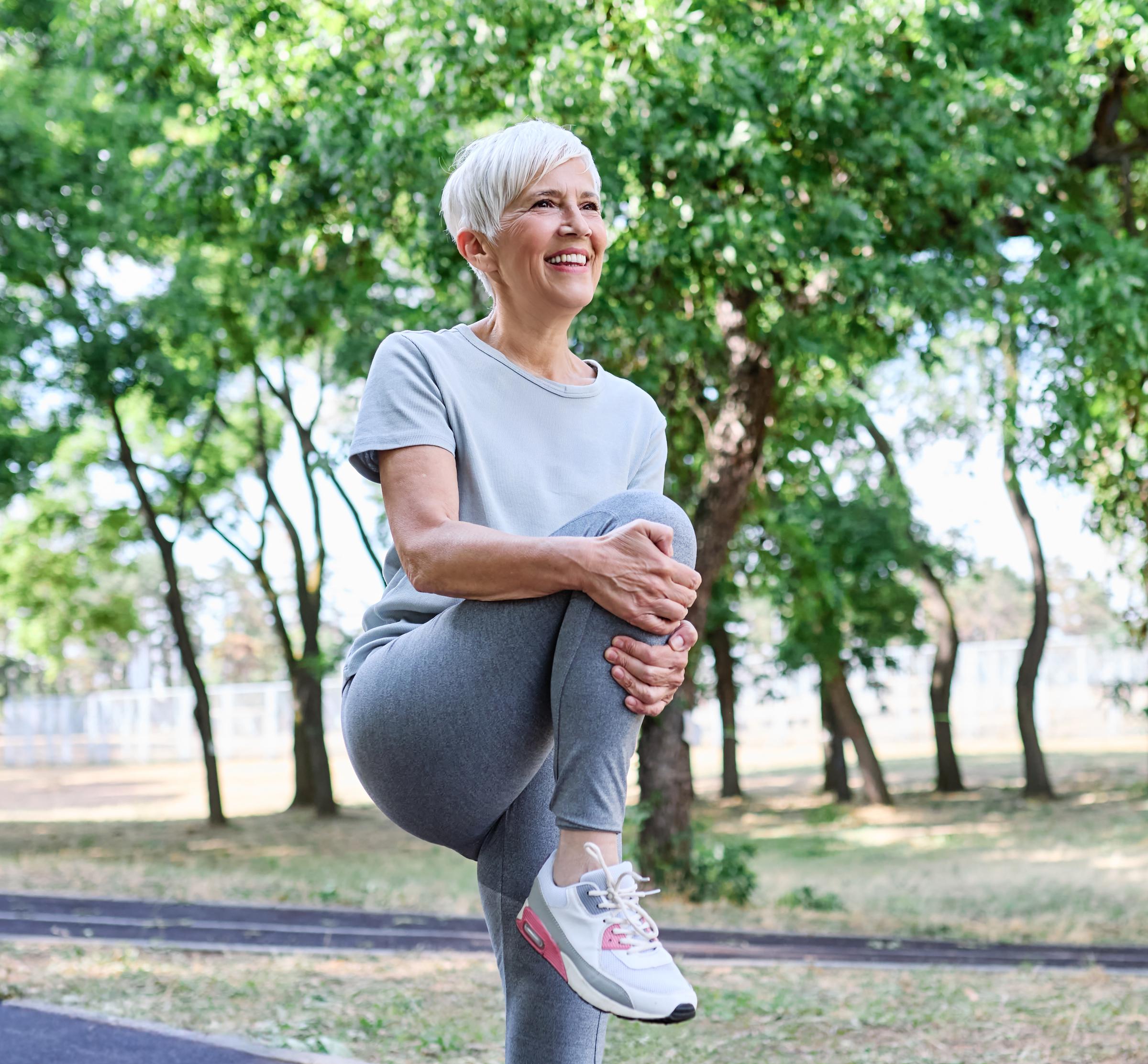 Kobieta wykonująca lekkie rozciąganie na zewnątrz | Źródło: Shutterstock