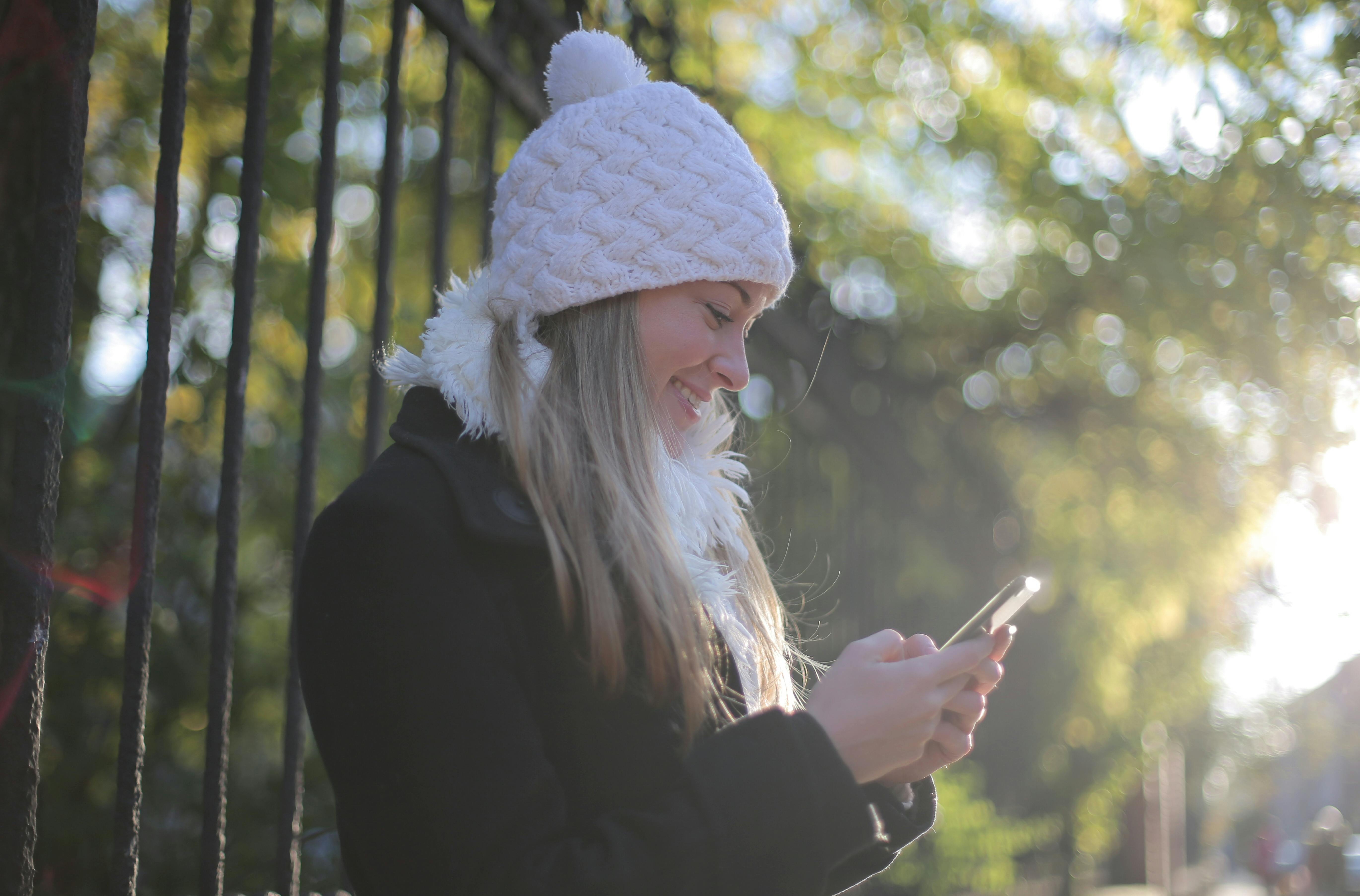 Kobieta uśmiechająca się, patrząc na swój telefon | Źródło: Pexels