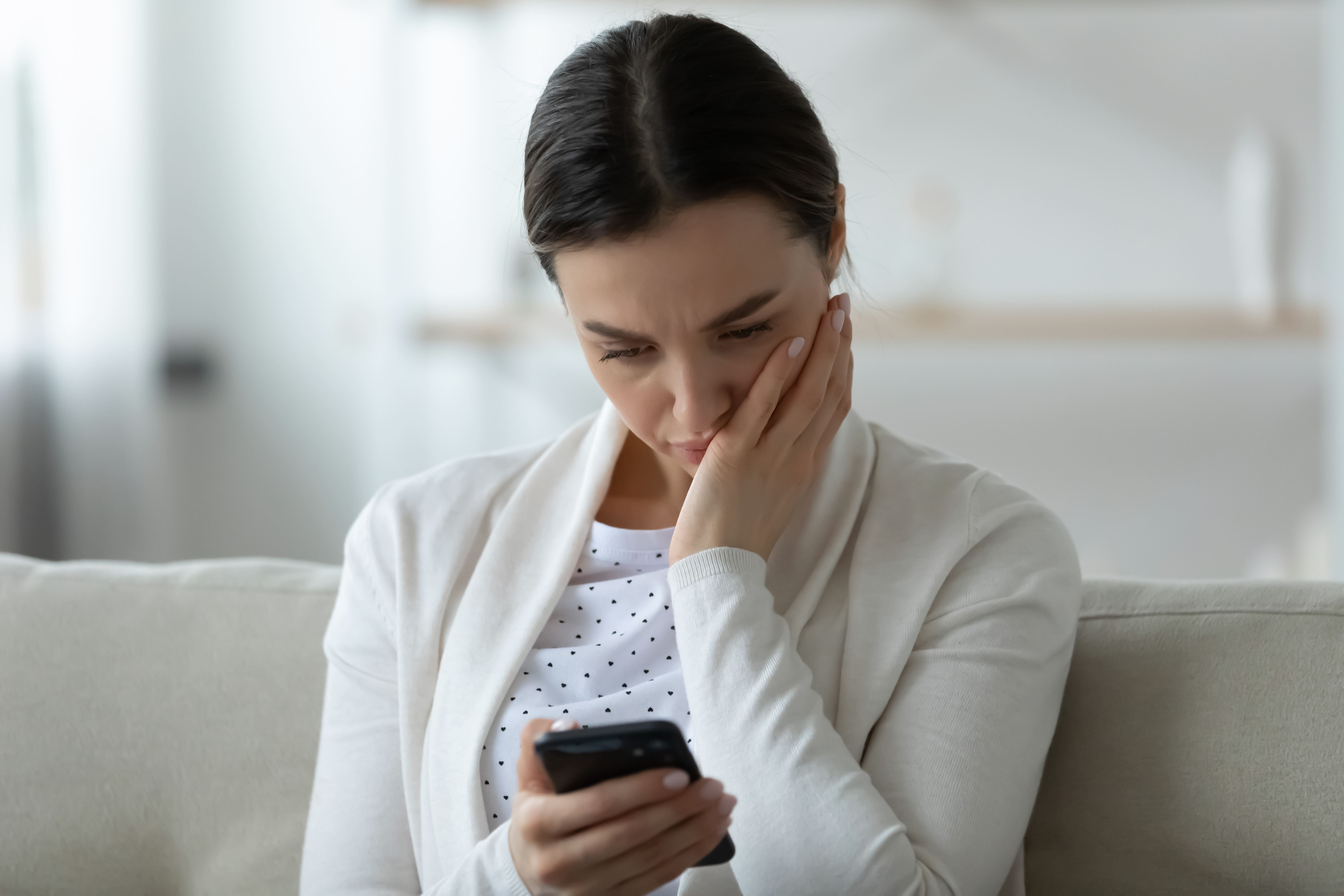 Zrozpaczona kobieta trzymająca smartfon | Źródło: Shutterstock
