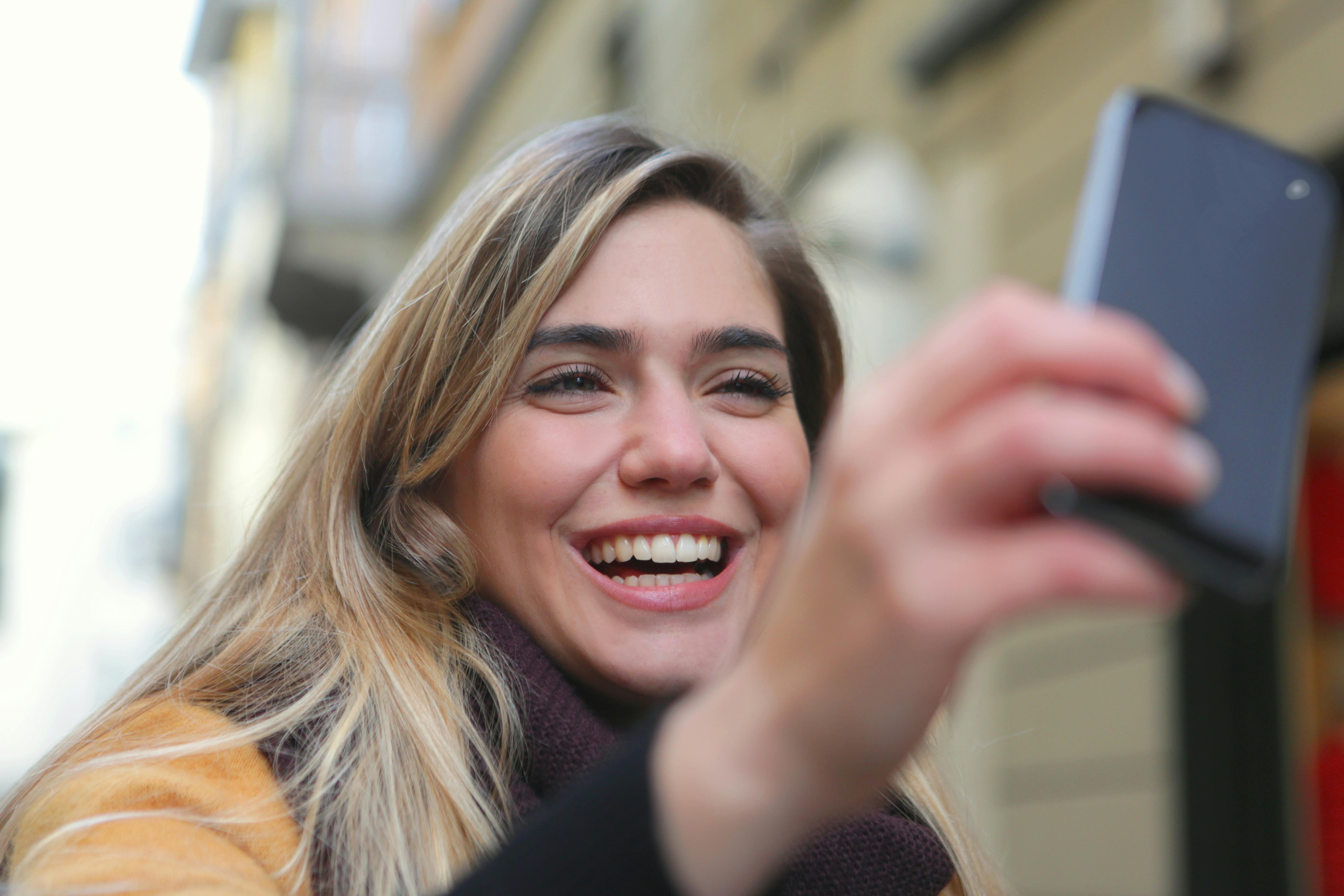 Kobieta śmiejąca się, patrząc na swój telefon | Źródło: Pexels