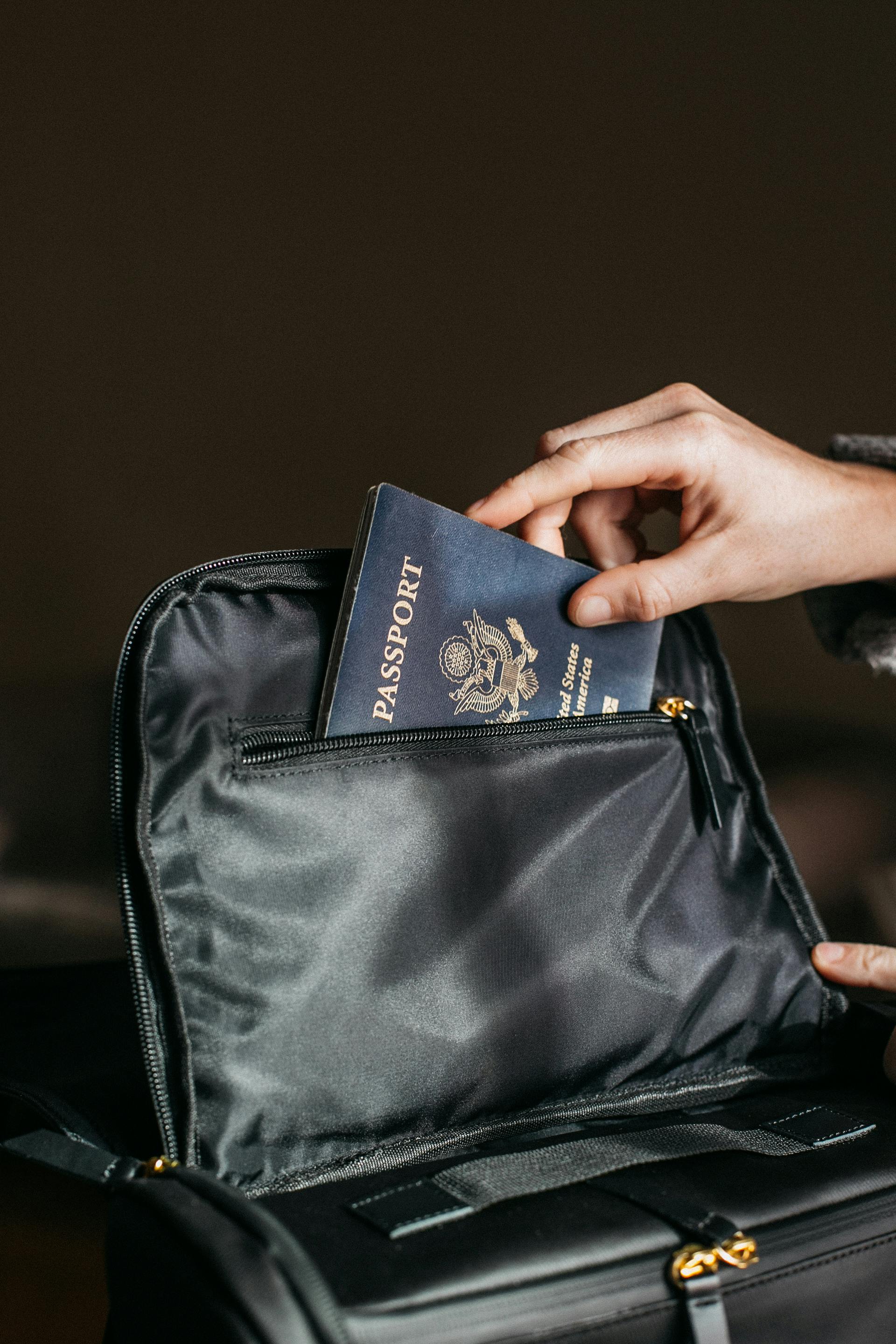 Zbliżenie na osobę wkładającą paszport do czarnej torby | Źródło: Pexels
