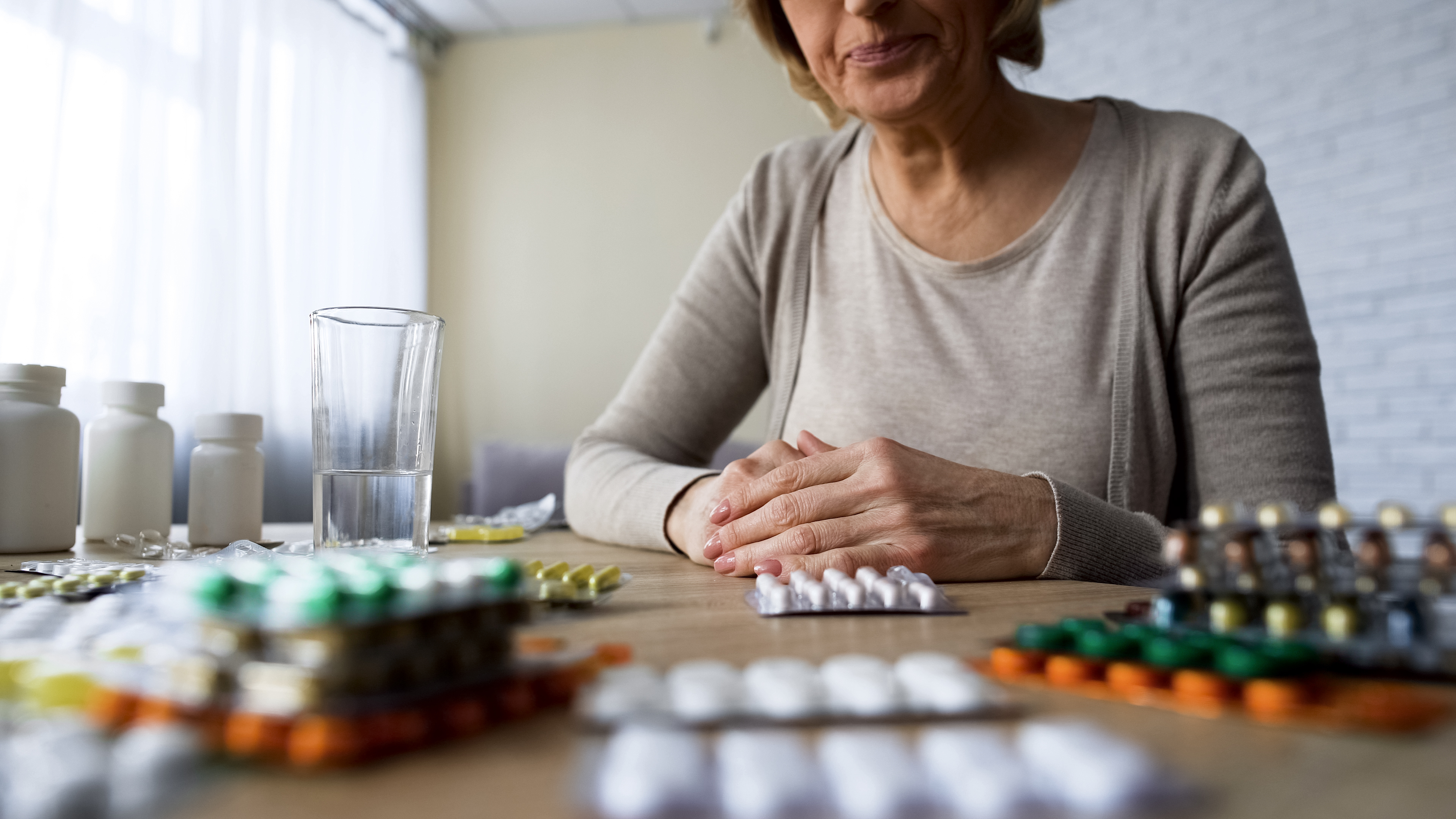 Kobieta z nadmiarem witamin i suplementów na stole | Źródło: Shutterstock