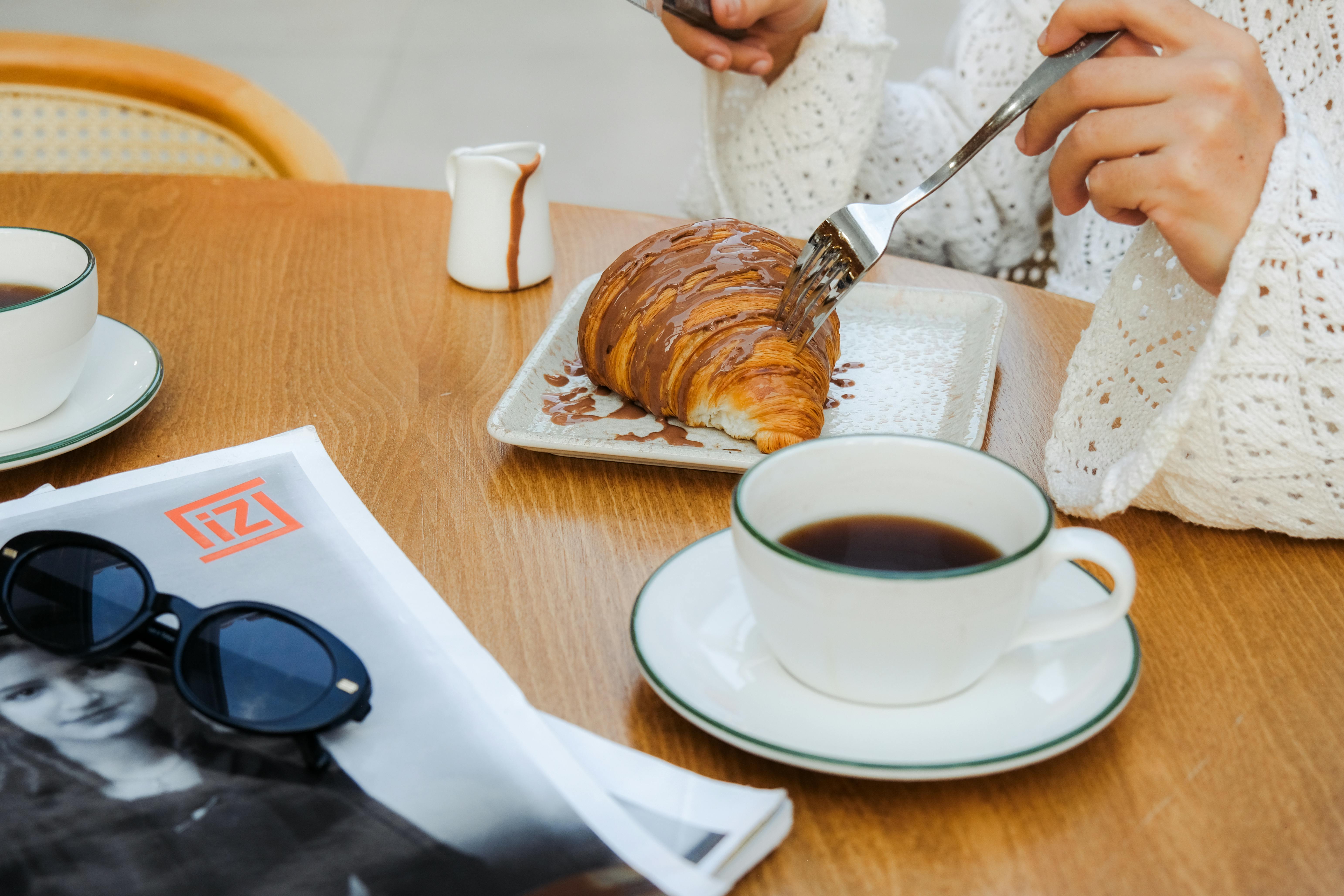 Kobieta jedząca rogalika w kawiarni | Źródło: Pexels
