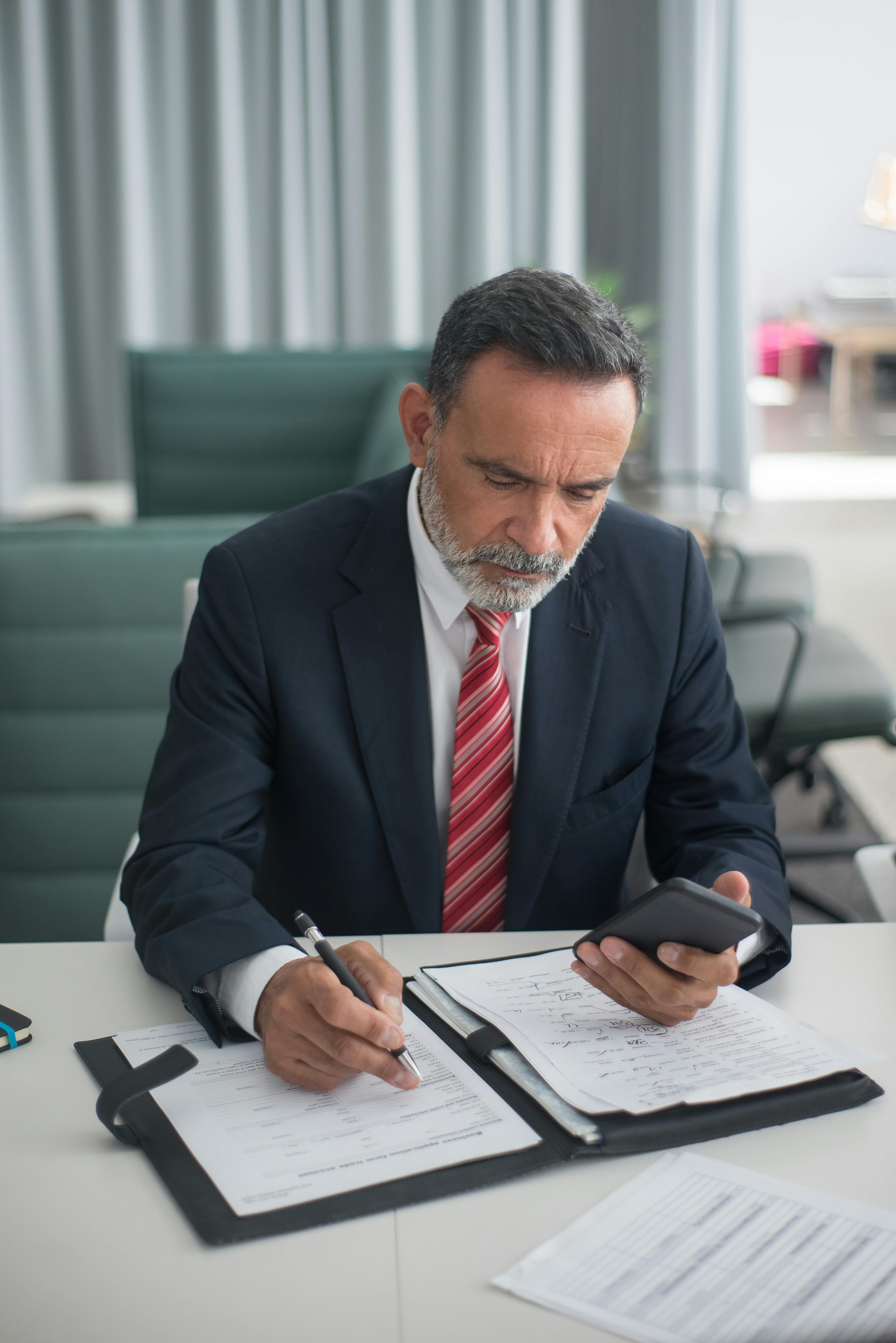 Mężczyzna trzymający telefon podczas pisania | Źródło: Pexels
