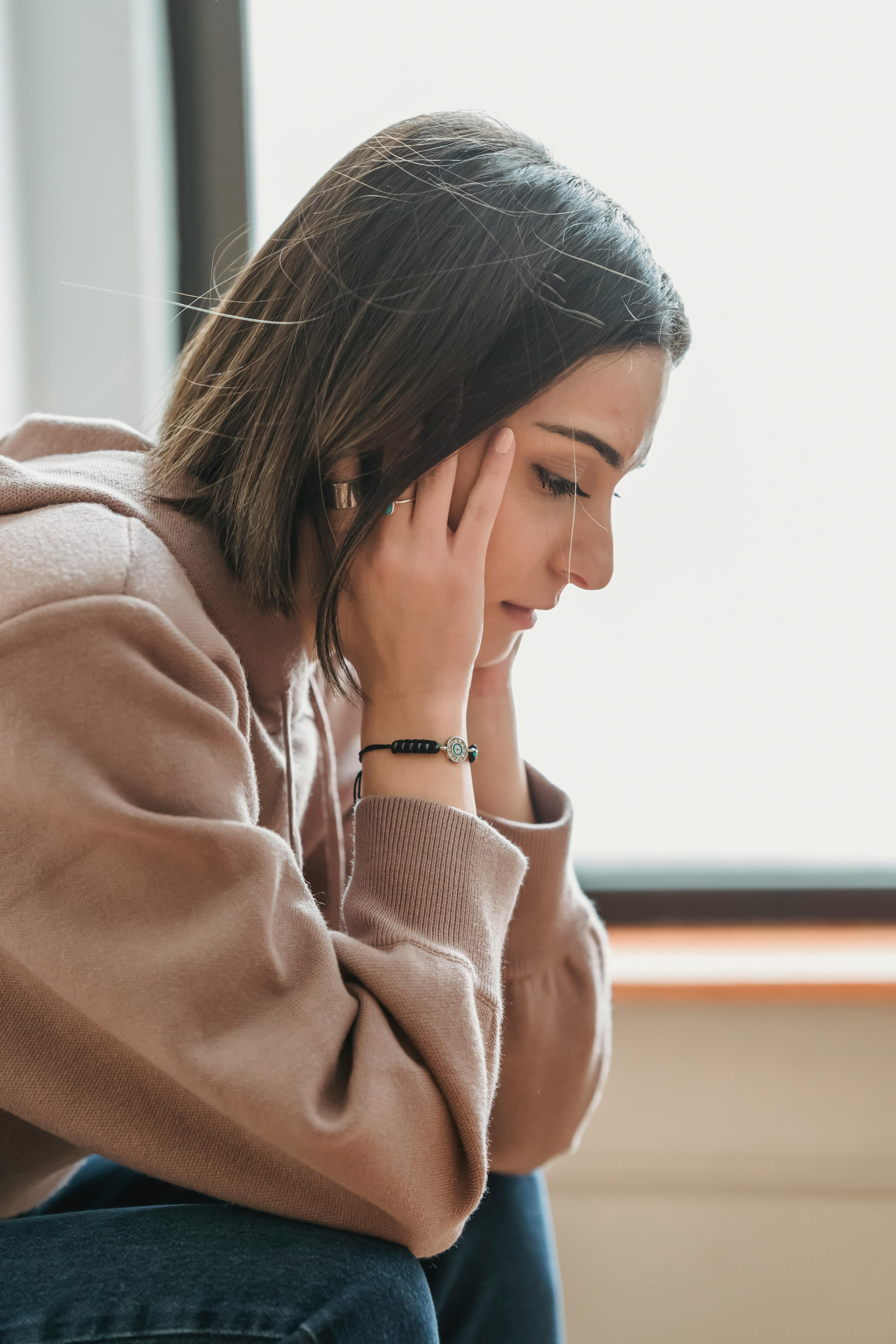 Smutna kobieta z głową opartą na dłoniach | Źródło: Pexels